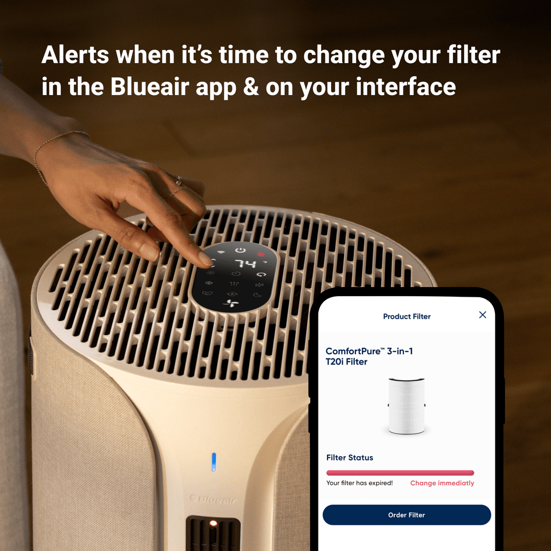 Air purifier with smartphone displaying Blueair app interface on a wooden background